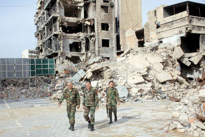 Syrian government forces walk on a heavily damaged street in the regime-controlled side of the northern city of Aleppo on Monday (AFP photo)