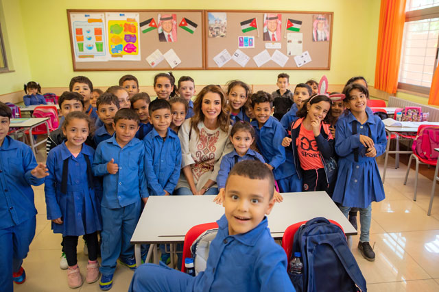 Her Majesty Queen Rania poses for a group photo with schoolchildren during a visit to Dulayl in Zarqa on Wednesday (Photo courtesy of Royal Court)