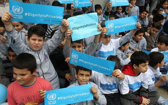 Palestinian refugees hold placards at a school belonging to the United Nations Relief and Works Agency for Palestinian Refugees (UNRWA) in the town of Sebline east of the southern Lebanese port of Saida, on March 12, 2018, during a protest against US aid cuts to the organization (AFP photo)