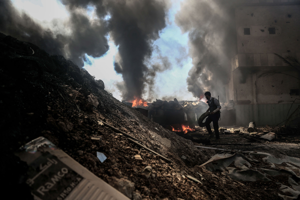 A fighter from the Jaish Al Islam throws a tyre onto a fire to keep the smoke billowing to give them coverage during battles with government forces, in the village of Tal Al Siwan area of the rebel-held stronghold of Douma, on the outskirts of Damascus, on Monday (AFP photo)