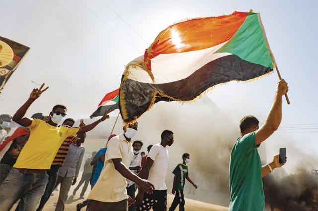 Sudanese youth wave the national flag as they rally in the streets of Khartoum, chanting slogans and burning tyres, to mark the second anniversary of the start of a revolt that toppled the previous government, on December 19 (AFP photo)