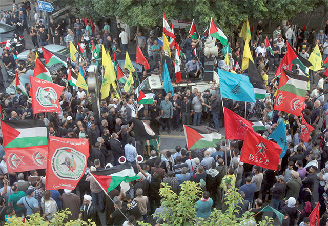 Supporters of Hizbollah and allied Palestinian factions in Lebanon lift flags and placards during a protest in the southern city of Sidon in solidarity with Palestinians in Gaza, on Saturday (AFP photo)