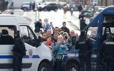 Onlookers gather behind a security cordon mannerd by CRS police officers and gendarmes on the sidelines of a ceremony at the Tomb of the Unknown Soldier at the Arc de Triomphe in Paris on Saturday (AFP photo)