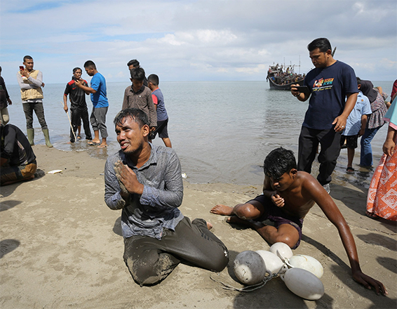 Newly arrived Rohingya refugees react after reaching the beach by swimming as others are stranded on a boat after the nearby community decided not to allow them to land but gave them water and food in Pineung, Aceh province, on Thursday (AFP photo)