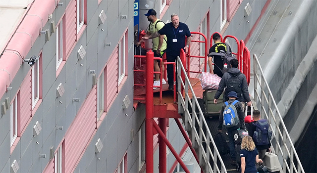 People carrying bags are seen walking up the gang-way into the Bibby Stockholm accommodation barge, moored to the quayside at Portland Port in Portland, on the south-west coast of England on August 7 (AFP photo)