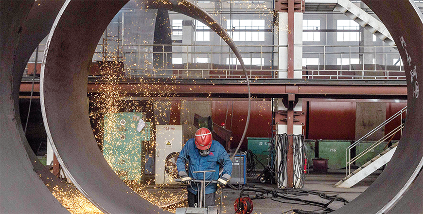 An employee works on a large construction equipment at a factory in Haian city, in China's eastern Jiangsu province, on Monday (AFP photo)