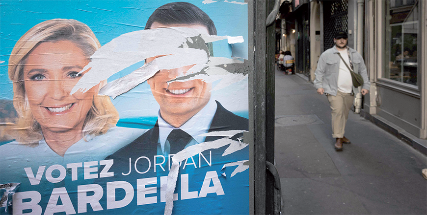A man walks along a street past an electoral poster of the French far-right Rassemblement National (RN) Party for the European elections with defaced portraits of party President Jordan Bardella and President of RN parliamentary group Marine Le Pen , in Paris on Monday (AFP photo)