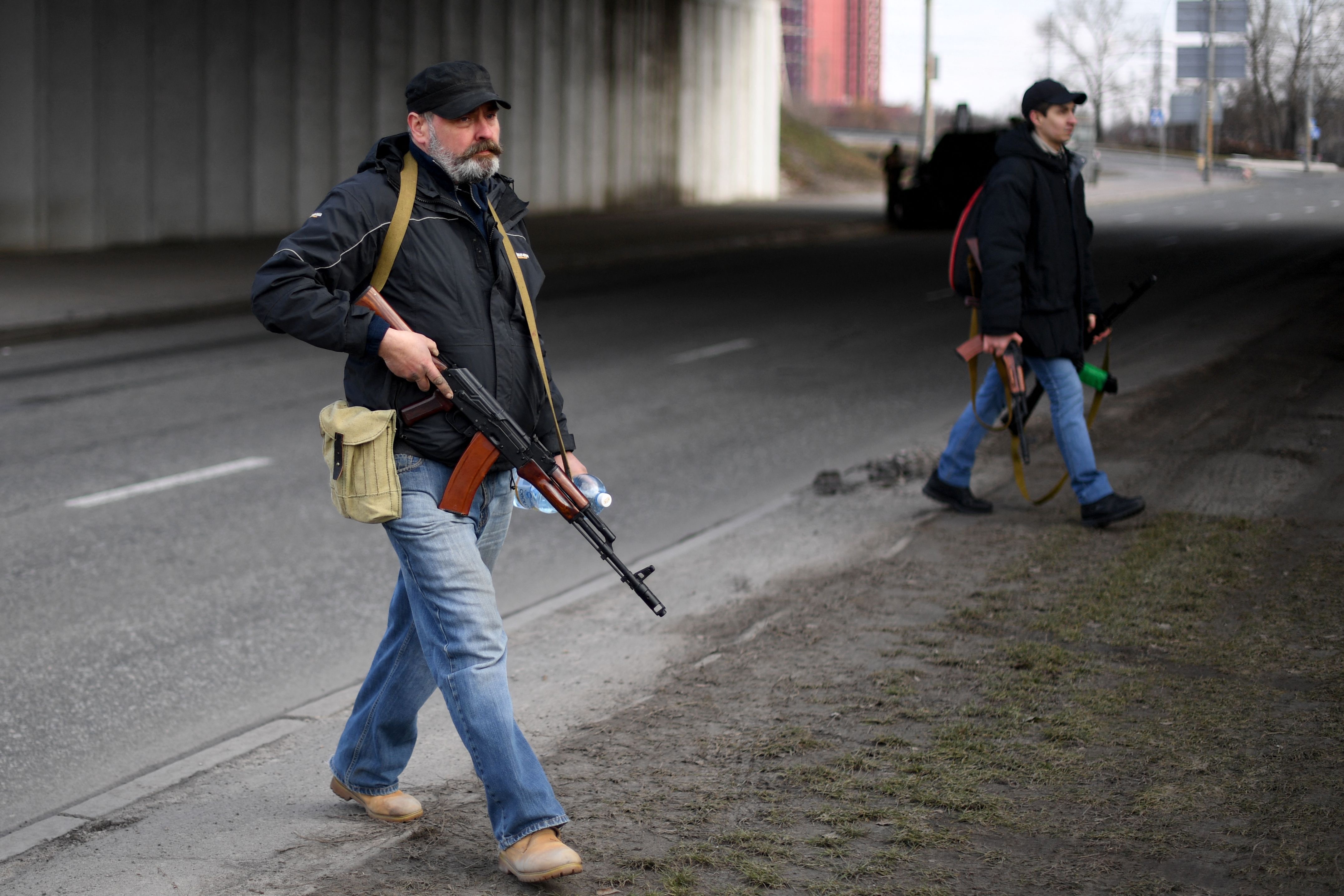 Volunteers, one holding an AK-47 rifle, protect a main road leading into Kyiv on Friday (AFP photo)