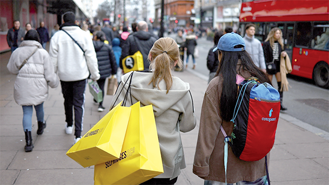 Shoppers carry their shopping bags along Oxford Street during the Boxing Day sales in London on Tuesday (AFP file photo)