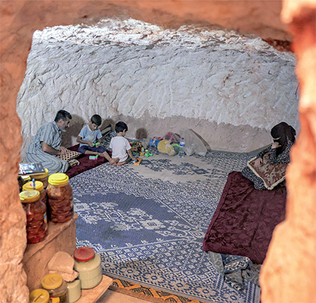 Ahmad Khalil, 53, sits with his family in a cave he carved manually with his children in five years, near his original home in the mostly abandoned village of Kansafra in the rebel-held south of Idlib province, on September 10 (AFP photo)