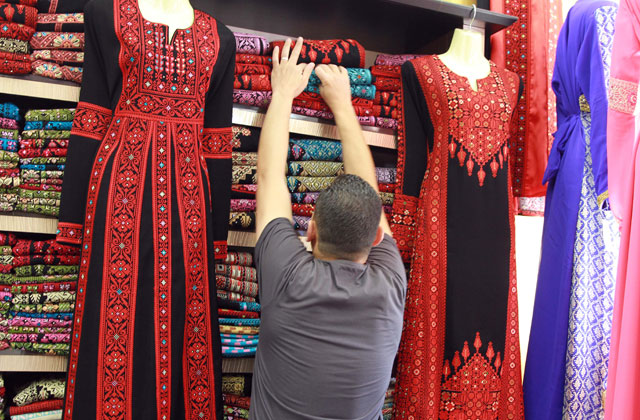A salesman arranges clothes on display at a shop in Amman recently (Photo by Hassan Tamimi)