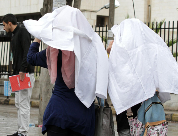 Medical students at the University of Jordan huddle under their white coats on Monday (Photo by Osama Aqarbeh)