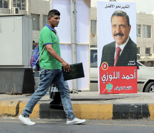 A pedestrian walks past a poster promoting a parliamentary candidate in Amman on Wednesday (Photo by Osama Aqarbeh)