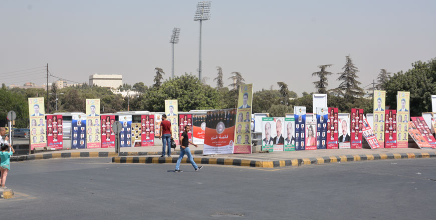 Pedestrians pass by election posters in Amman recently (Photo by Amjad Ghsoun)