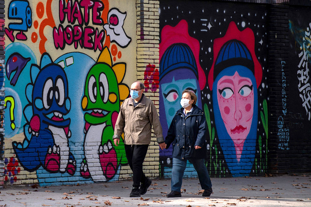A couple walk past murals in central Barcelona on Thursday. Spain's death toll surged over 40,000 with infections passing the 1.4 million mark, making it the country with the fourth-highest death rate within the EU (AFP photo)