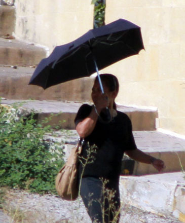 A woman carries an umbrella while walking in Amman on Saturday to shield herself from the sun (Photo by Hassan Tamimi)