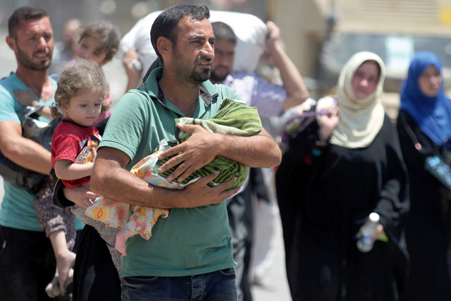 A man carries an infant while fleeing with other civilians from the Old City of Mosul as Iraqi forces advance on Tuesday, during the ongoing offensive to retake the last district still held by the Daesh group (AFP photo)