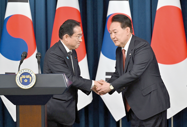South Korean President Yoon Suk-yeol (right) shakes hands with Japanese Prime Minister Fumio Kishida  during a joint press conference after their meeting at the presidential office in Seoul, on Sunday (AFP photo)