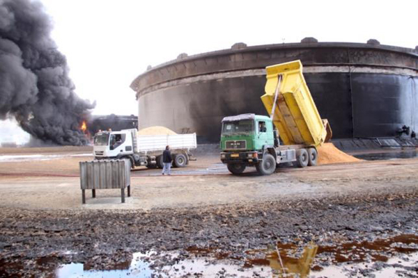 This photo shows  smoke rising from burning oil storage tanks in the port of Ras Lanuf, Libya, January 23 (Reuters file photo)