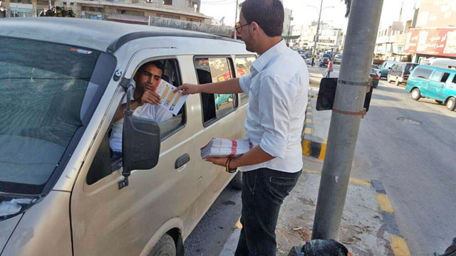 An Independent Election Commission volunteer distributes pamphlets on voter lists to motorists late last month (Photo courtesy of IEC)