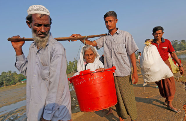 Boduuzzol Kharun, 97, is carried by her family members as they arrive at a port after crossing the Bangladesh-Myanmar border, in Teknaf (Reuters photo)