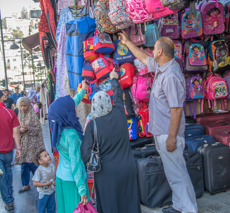A salesman shows schoolbags to customers at a shop in downtown Amman this month (Photo by Amjad Ghsoun)