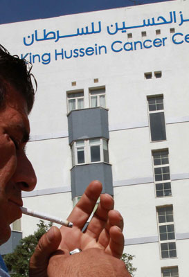 A man lights a cigarette in front of the King Hussein Cancer Centre in Amman on Saturday (Photo by Hassan Tamimi)