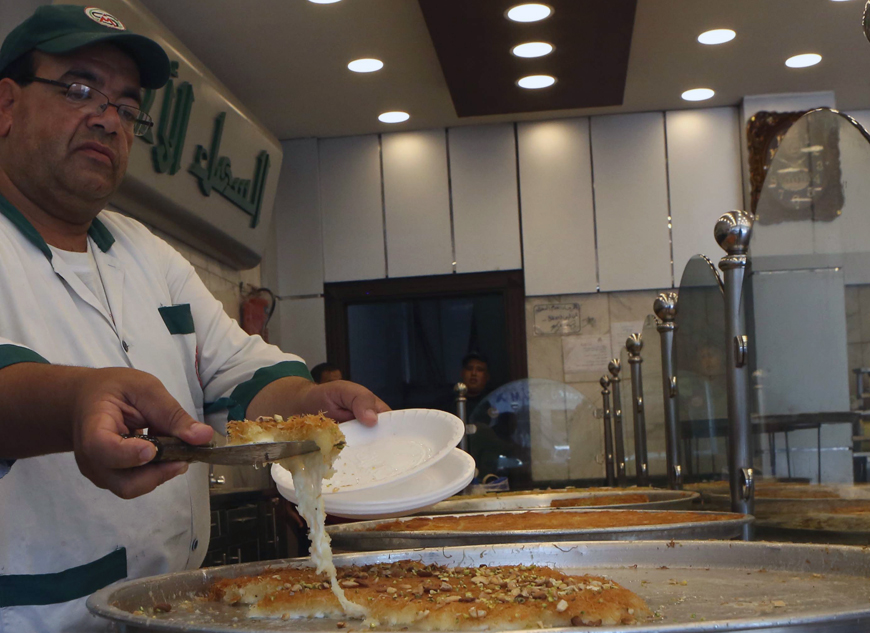 A worker at a sweets shop in Amman prepares knafeh on Tuesday (Photo by Hassan Tamimi)