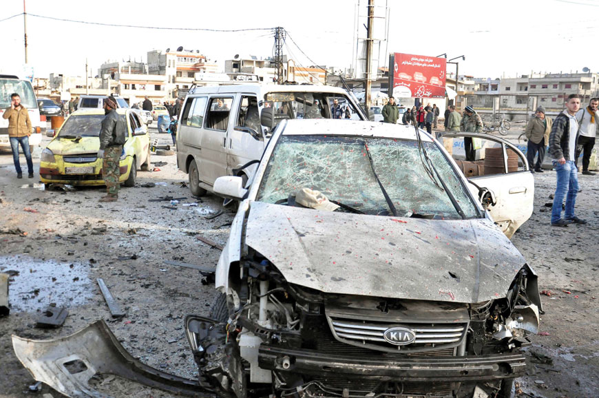 In this photo released by the Syrian official news agency SANA, Syrian citizens gather at the scene where twin bombs exploded at a government-run security checkpoint, in the neighbourhood of Zahra, in Homs province, Syria, Tuesday (AP photo)