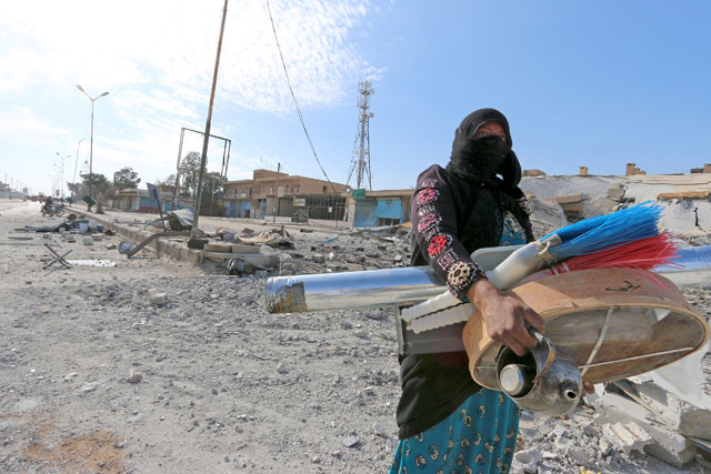 A woman carries goods she allegedly looted in Shadadi town, Hasaka countryside, Syria, on Friday  (Reuters photo by Rodi Said)