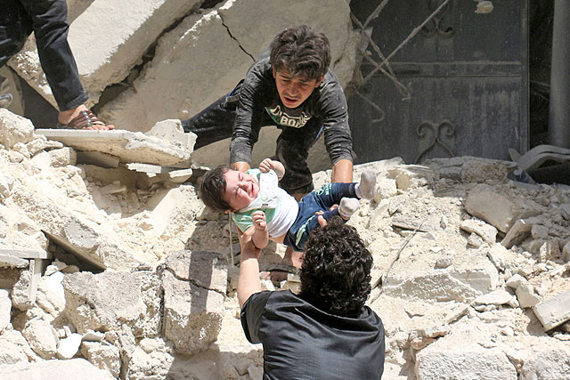 Syrians evacuate a toddler from a destroyed building following a reported air strike on the rebel-held neighbourhood of  Al Kalasa in the northern Syrian city of Aleppo on Thursday (AFP photo)