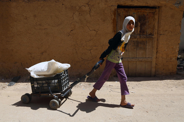 A Syrian girl pulls a cart after receiving from the local council aid parcels provided by the UN World Food Programme and the Syrian Arab Red Crescent on Wednesday, in the rebel-held village of Saqba, on the eastern outskirts of the capital Damascus (AFP photo)
