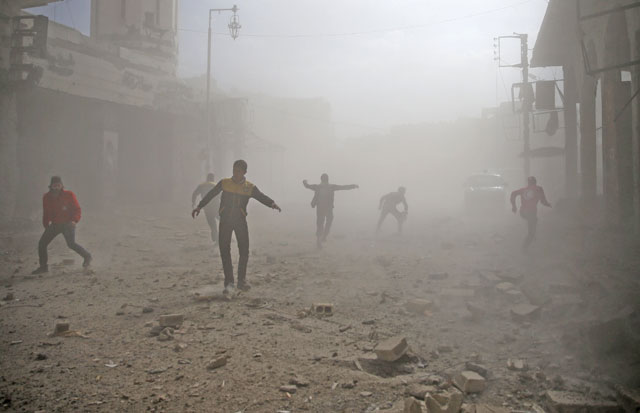Civil defence members and civilians are seen running after an air raid in the besieged town of Douma in eastern Ghouta in Damascus, Syria, on Tuesday (Reuters photo)