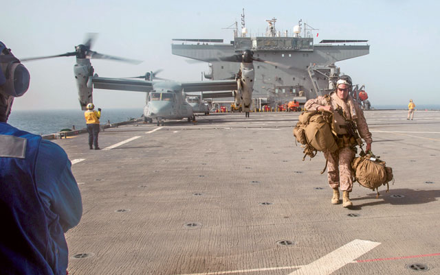 In this handout photo provided by the US Marine Corps, US Marine Corps Gunnery Sgt. David Arendt carries his gear across the flight deck of the USS Lewis B. Puller upon embarkation in the Arabian Gulf, on May 11 (Reuters photo)