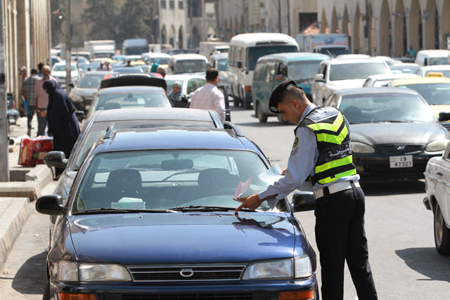 A traffic police officer leaves a parking ticket on a vehicle's windshield in Amman on Thursday (Photo by Nader Daoud)