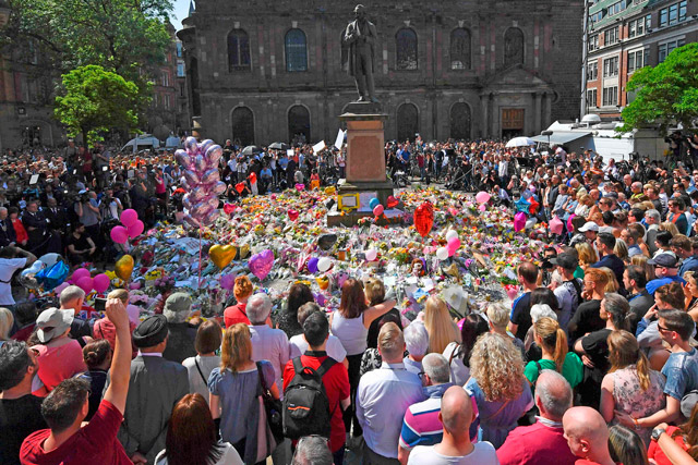 People stop to observe a minute's silence in St Ann's Square gathered around the tributes, in central Manchester, northwest England, on Thursday, as a mark of respect to the victims of the May 22 terror attack at the Manchester Arena (AFP photo)