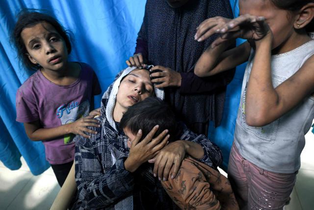A wounded Palestinian woman from the Baraka family is surrounded by her children upon their arrival at Nasser Hospital in Khan Yunis in the southern Gaza Strip following Israeli air strikes that hit their building on November 13 (AFP photo)