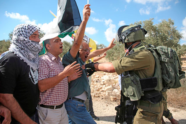 An Israeli soldier pushes back Palestinian demonstrators during a weekly demonstration against the expropriation of Palestinian land by Israel in the village of Kufur Qaddum, near Nablus, in the occupied West Bank on Saturday (AFP photo)