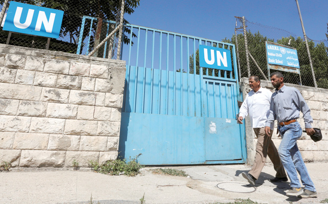 Palestinians pass by the gate of an UNRWA-run school in Nablus in the occupied West Bank on Monday (Reuters photo)