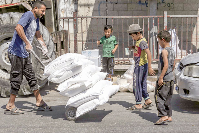 A Palestinian man transports bags of flour outside an aid distribution centre run by the United Nations Relief and Works Agency in the central Gaza Strip refugee camp of Bureij on Wednesday (AFP photo)