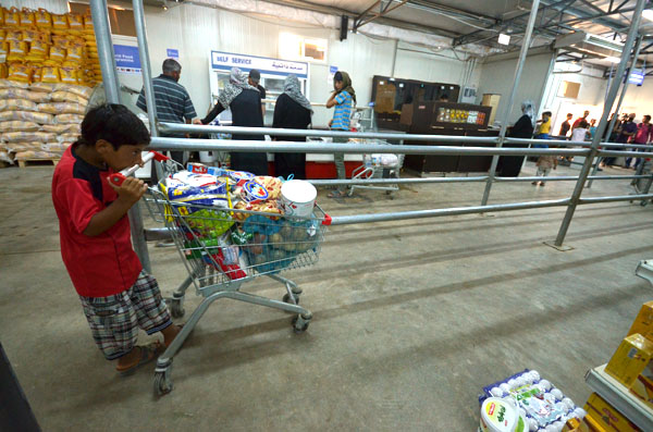 A Syrian refugee pushes a cart filled with food and supplies at a market at the Zaatari camp, some 90km northeast of Amman, recently (Photo by Muath Freij)