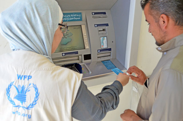 A member of the WFP team assists a Syrian refugee in using the blockchain method in Azraq refugee camp recently (Photo courtesy of World Food Programme)
