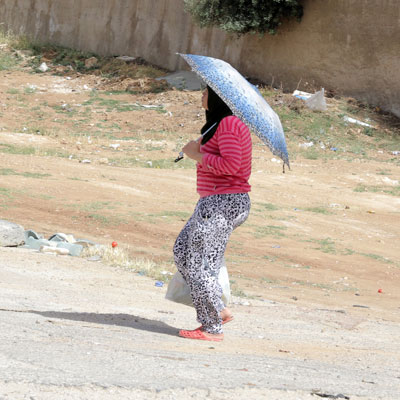 A woman carries an umbrella to shield herself from the sun in Amman recently (Photo by Osama Aqarbeh)