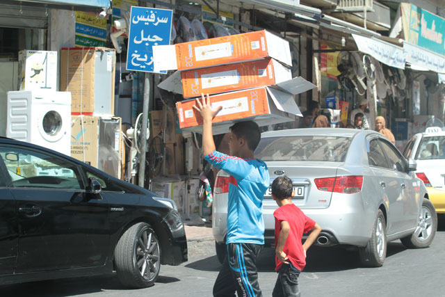 A young man carries boxes of fans on a street in Amman on Thursday (Photo by Hassan Tamimi)