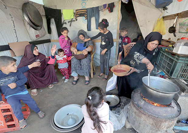Displaced Palestinians who fled Khan Yunis prepare food in Rafah on the southern Gaza Strip on Thursday (AFP photo)