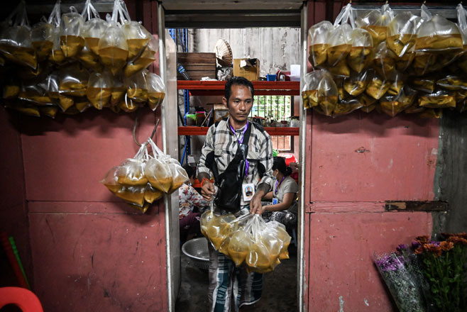   This photo taken on Wednesday in Yangon shows a volunteer preparing free meals to distribute (AFP photo)