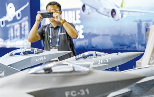 A man takes photograph of miniature models of China's fighter jets ahead of the Singapore Airshow in Singapore on Monday (AFP photo)