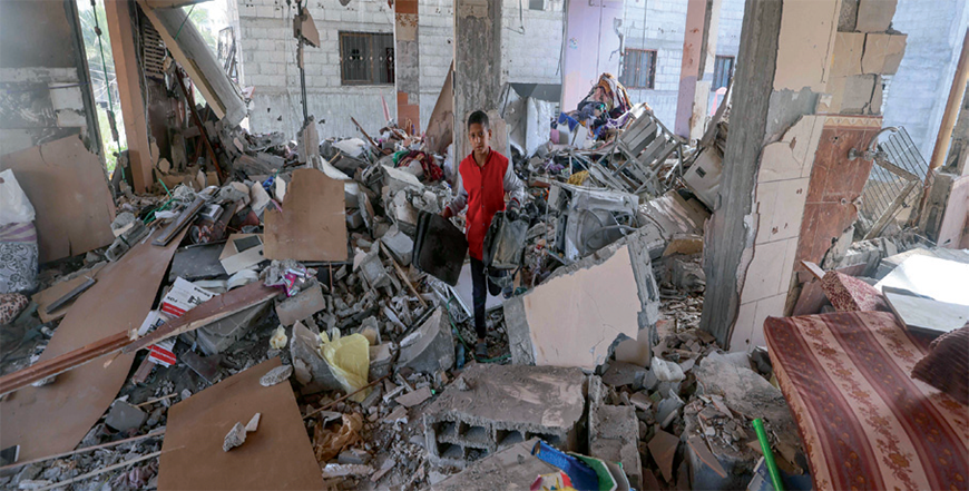 A Palestinian youth salvages items from a damaged apartment following overnight Israeli bombardment in Rafah in the southern Gaza Strip on Thursday (AFP photo)
