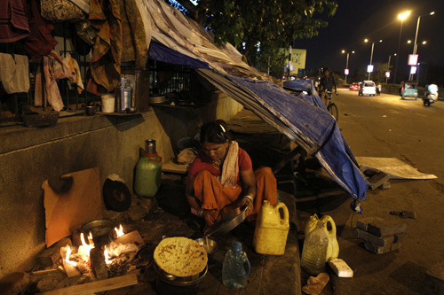 An Indian woman prepares food outside her makeshift dwelling on a pavement in Ahmadabad, India, on Friday (AP photo)