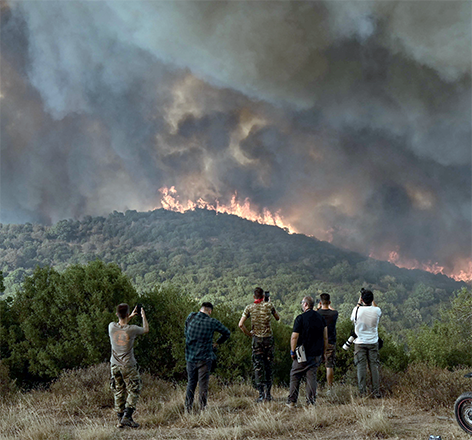 People look at the wildfire raging in a forest in Sikorahi, near Alexandroupoli, northern Greece, on Wednesday (AFP photo)